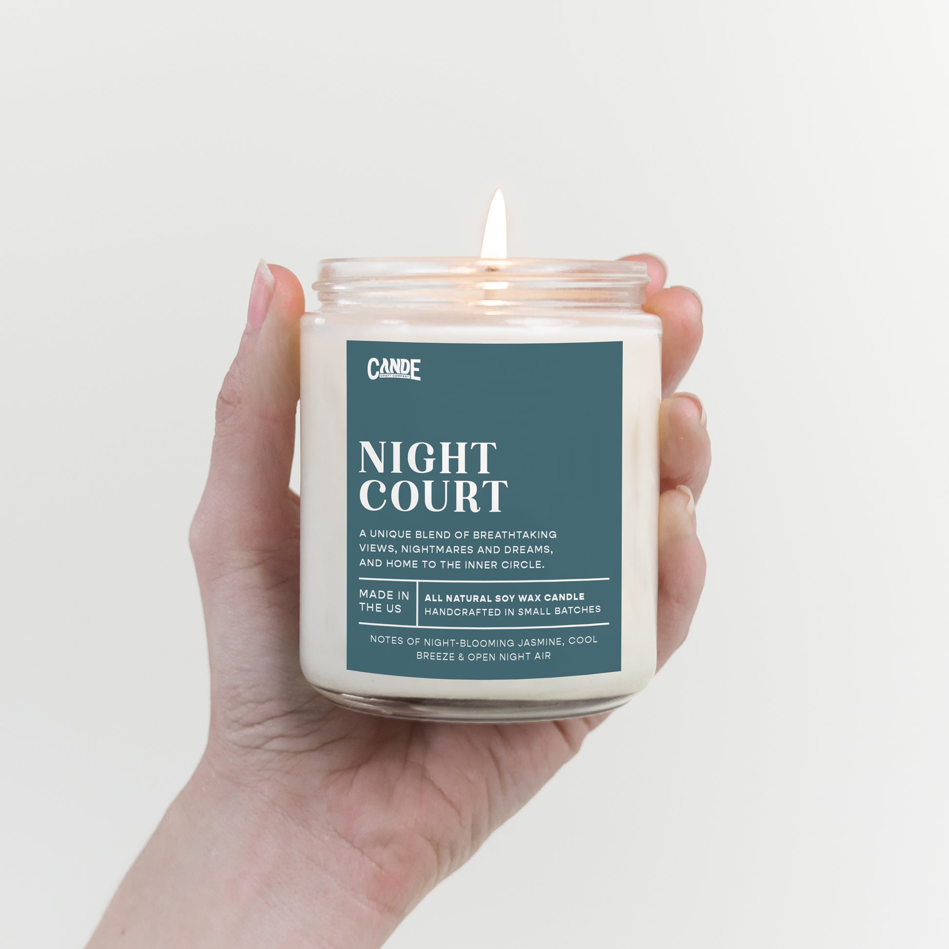 Hand holding a candle labeled 'Night Court' against a light background
